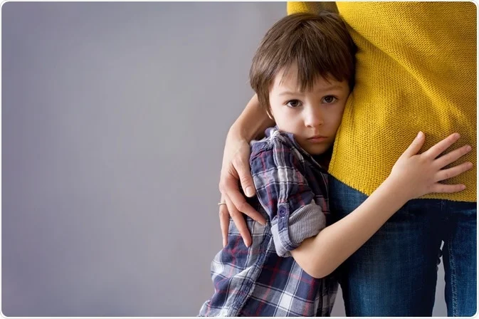 Sad child hugging a parent's leg